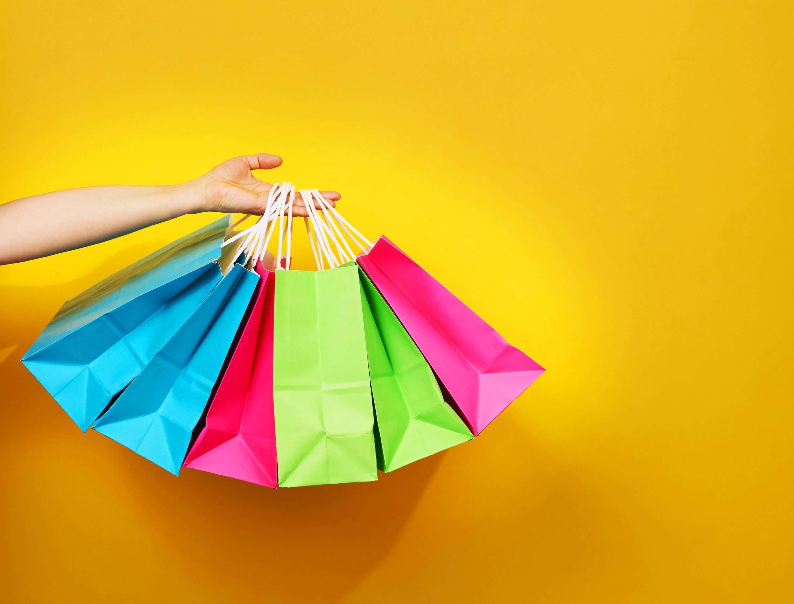 female hand holds a paper disposable bag with handles for groceries and clothes. Recyclable packaging. Zero waste. Sale